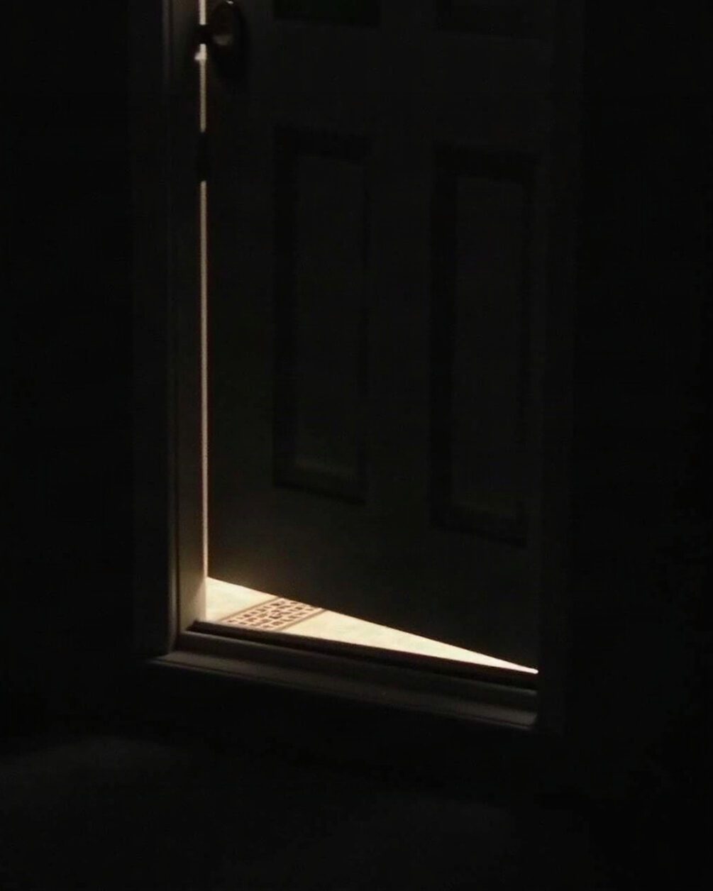 An exterior door threshold seen from inside at night, small gap of darkness beneath the door
