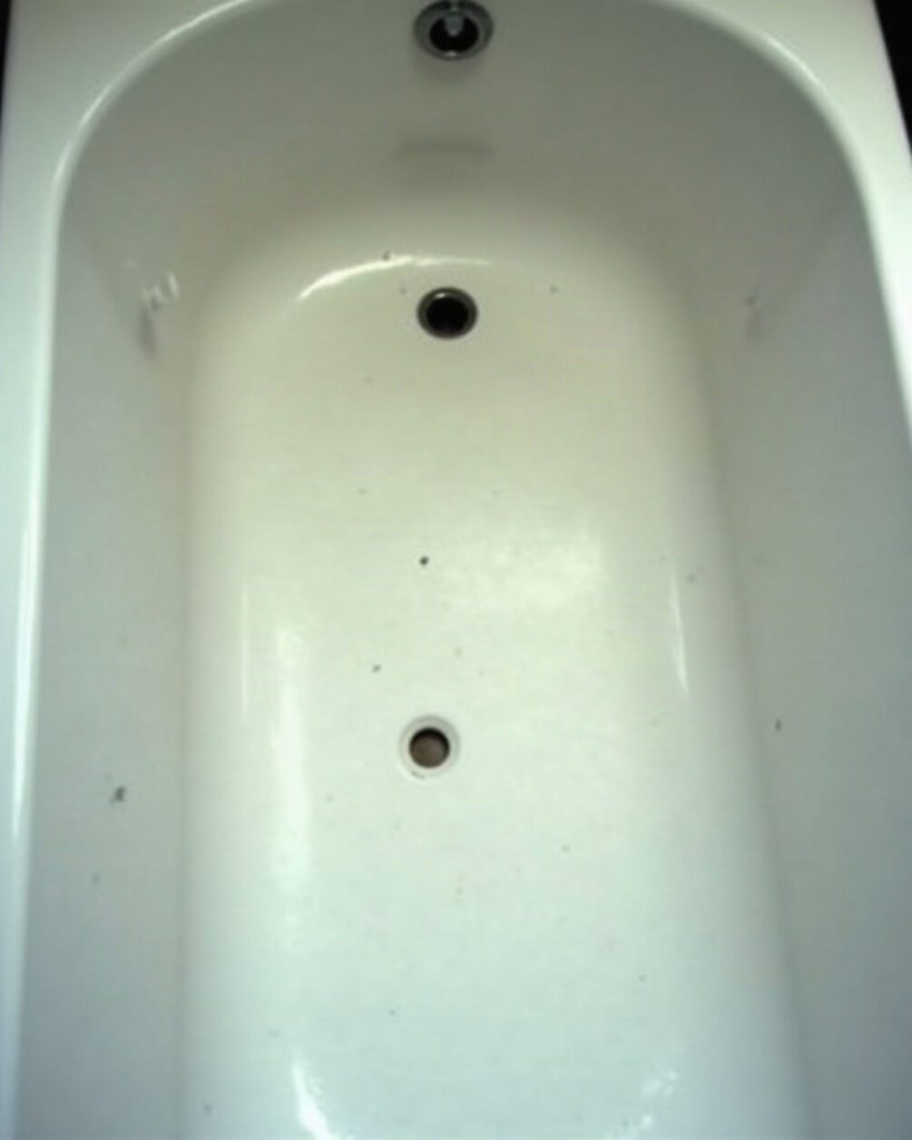 Empty white bath seen from above with smooth enamel sides under an overhead light